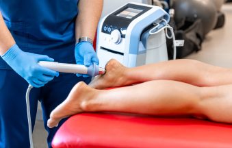 Shock wave therapy, the magnetic field, rehabilitation, physiotherapist doctor performs surgery on a patient's heel.